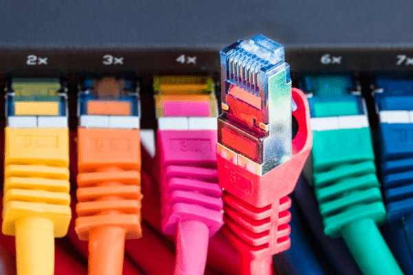 A close-up of multiple colorful Ethernet cables plugged into a network switch, with a red cable slightly disconnected, representing structured cabling and office network wiring solutions that ensure seamless internet connectivity.